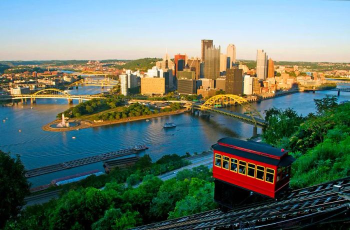 The iconic red Duquesne Incline climbs the steep slopes of Mt Washington, offering stunning views of Downtown Pittsburgh along with the Allegheny, Monongahela, and Ohio Rivers in the distance.