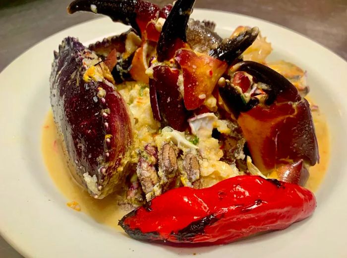 Generous chunks of purple crab nestled in a savory sauce alongside a large grilled red pepper.