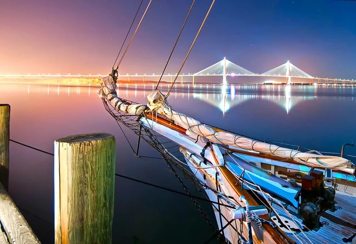 A photo captures the bow of a ship in the foreground, with a modern bridge in the background.