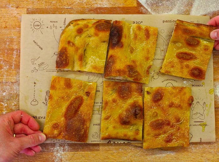 From above, hands reach for slices of pizza topped with dough, presented on an illustrated menu.