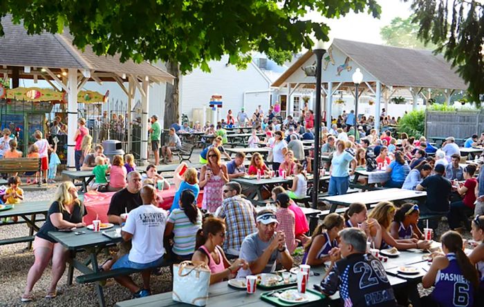 A sunny outdoor seating area where guests enjoy meals at picnic tables.