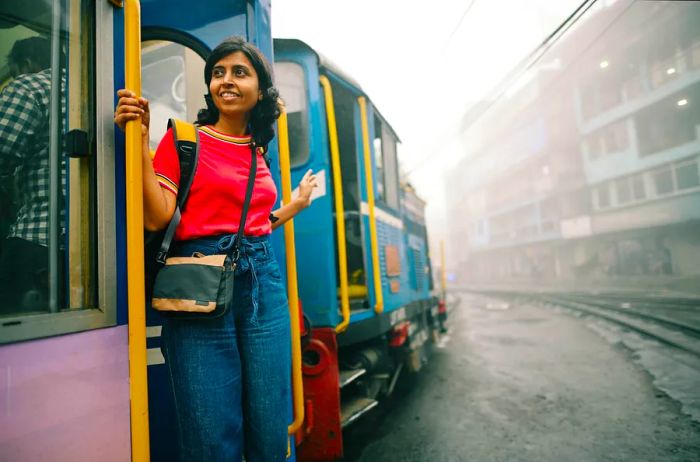 A woman stands at the door of a tourist train in Darjeeling.