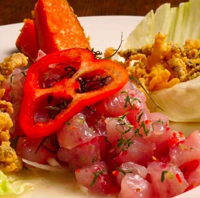 Chunks of pink fish topped with a slice of pepper, accompanied by other garnishes.