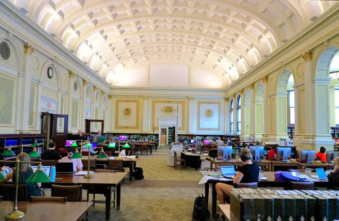 Visitors gather at tables in the main reading area of the Carnegie Library of Pittsburgh in Oakland.