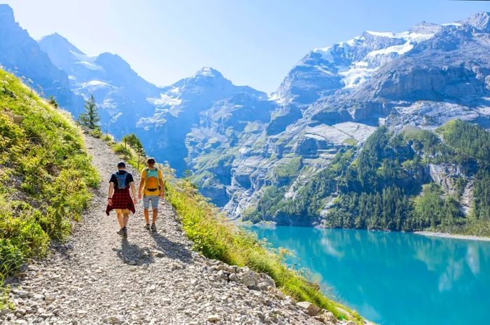 Two men hiking through stunning alpine scenery during summer, embracing the beauty of nature in the Swiss Alps.