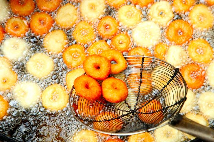 Vada (lentil-flour fritters) frying in oil in South India.