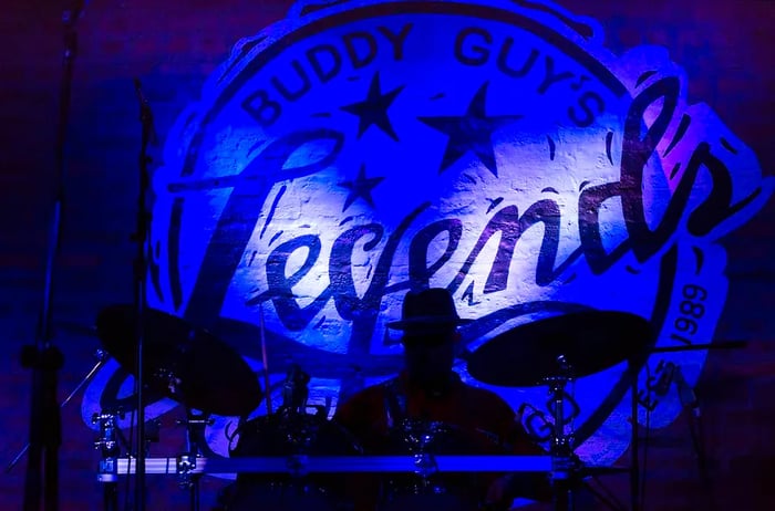 A drummer captivates the audience at Buddy Guy's Legends jazz club in Chicago, Illinois, illuminated by soft blue lights.