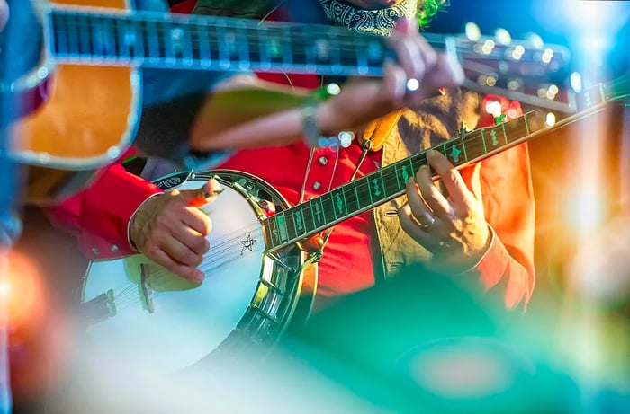 A close-up of a person playing the banjo while dressed in traditional Western attire. Nashville.