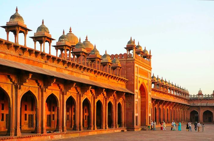 A stunning red-stone fortress with visitors walking through its gates