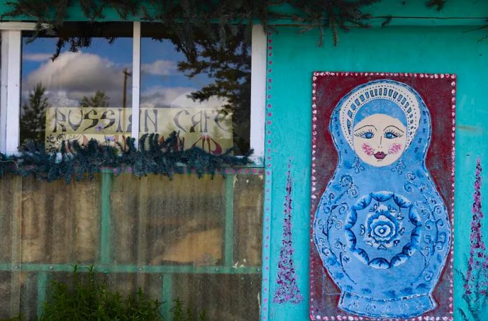 A painting of a blue doll adorns the wall of a building.