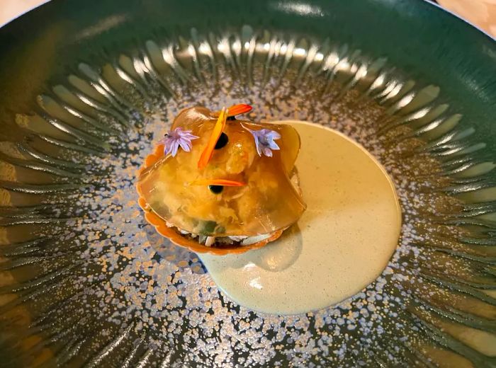 A bite-sized dish shaped like a scallop on a plate.