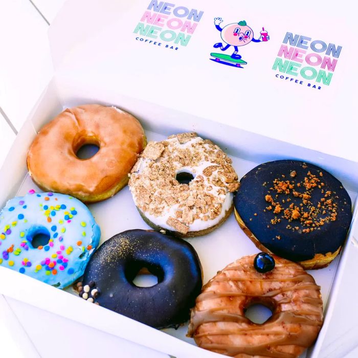 A vibrant assortment of doughnuts displayed in a box featuring a cartoonish doughnut logo.