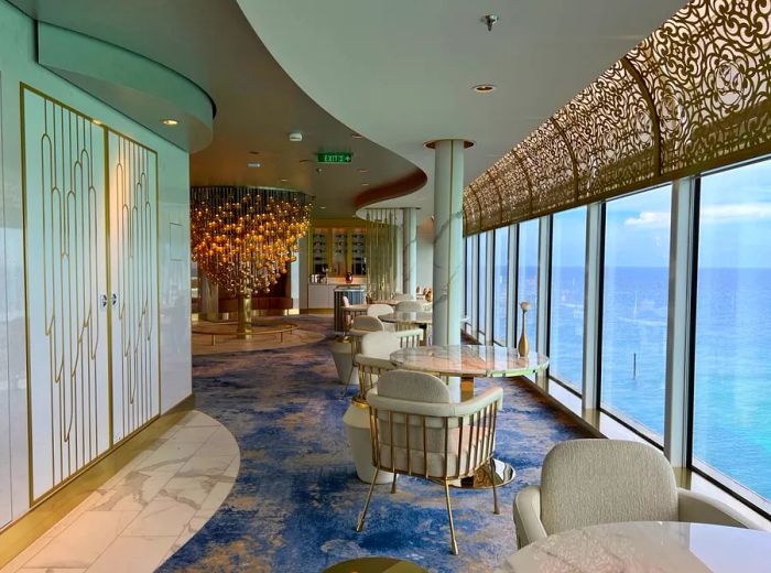 A bright white and gold dining area features large windows offering stunning water views.