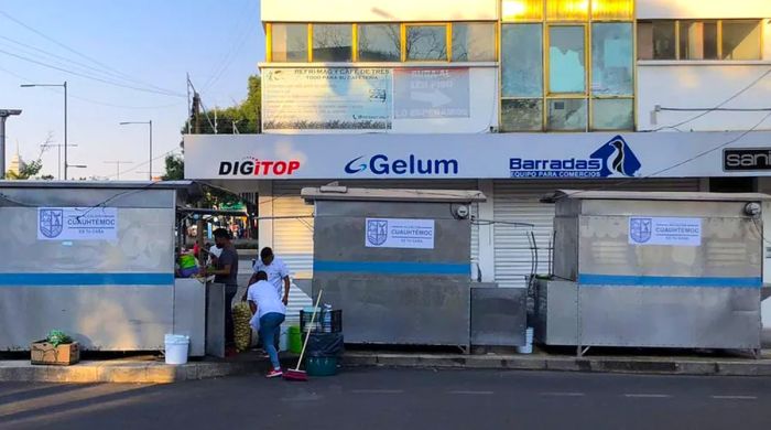 In the morning, workers clean a street around three food stalls, each adorned with government signage instead of traditional graphic advertisements.