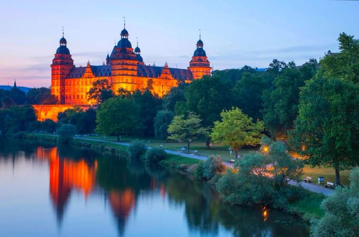 Schloss Johannisburg Palace and its parklands along the Main River at dusk, Bavaria, Germany.