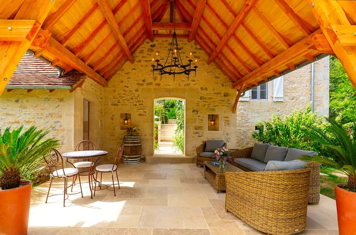 A covered walkway features a vaulted wooden ceiling and cozy loungers.