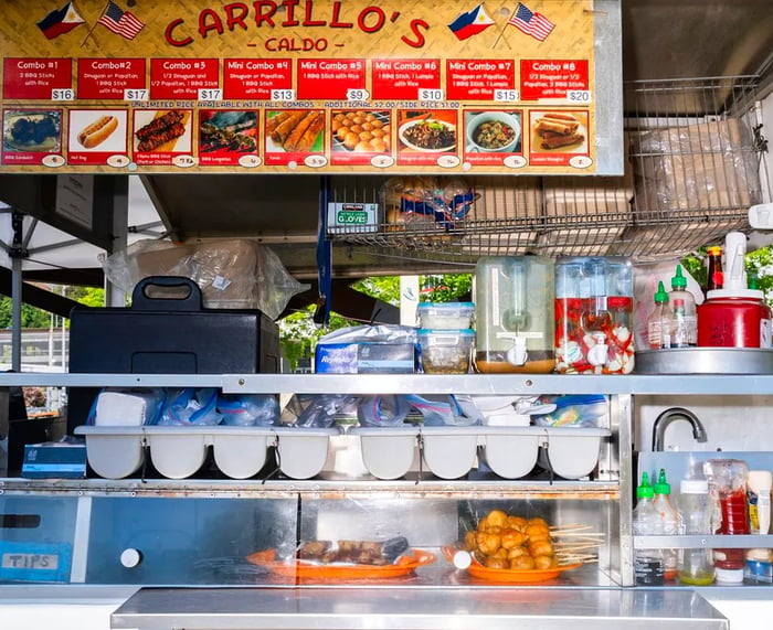 Inside a food cart featuring a sign that reads “Carillo’s,” showcasing a variety of Filipino delicacies.