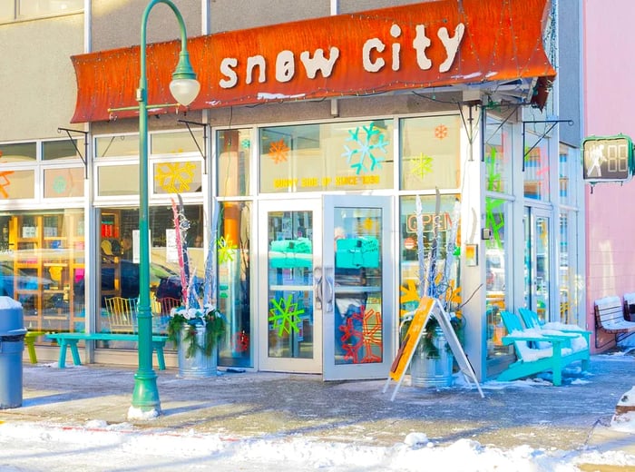 A restaurant facade with numerous glass panels reflecting sunlight, featuring a sign that says Snow City.