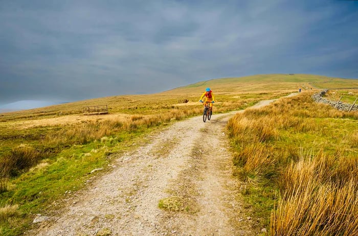 A cyclist rides along the Pennine Bridleway near Great Knoutberry Hill, England.