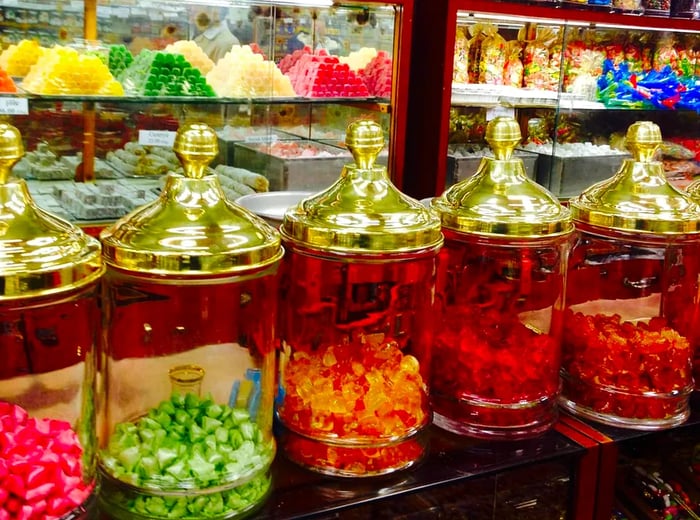 A display of large, ornate, semi-transparent red containers filled with a variety of candies.