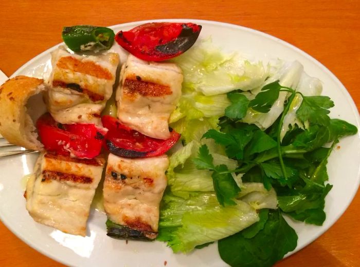 Aerial view of two grilled fish fillets served with a side salad on a plate.