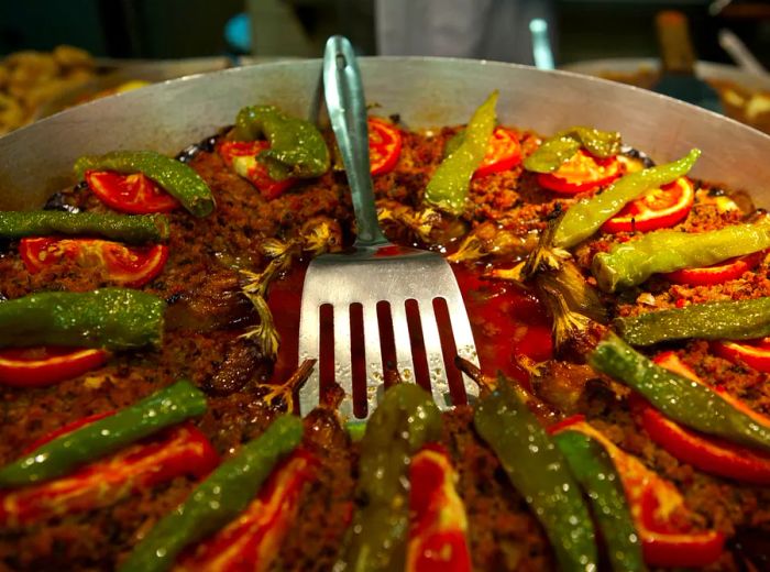 A large tray of stuffed eggplants with a big metal spatula placed in the center.