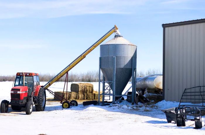 Industrial farming machinery stands on a snowy field.