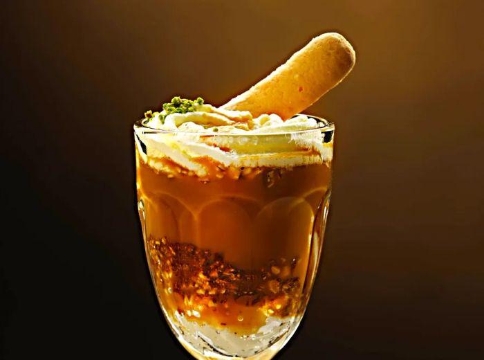 A decorative glass brimming with ice cream, drizzled with caramel, and topped with a piece of brittle.