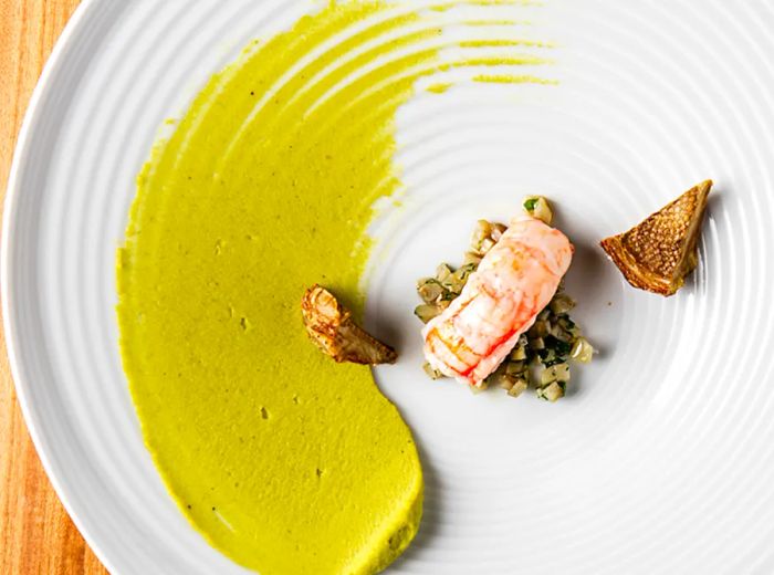 From above, a slice of fish rests on a mound of grains, accented by a vibrant yellow sauce.