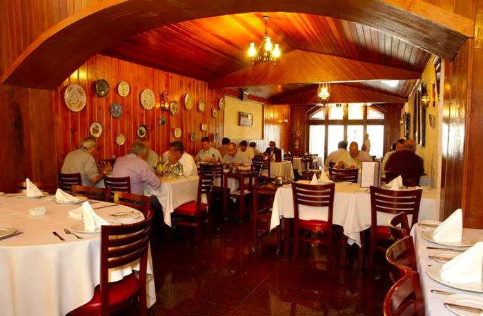 A dining area adorned with wood paneling, featuring an arched ceiling and tables dressed in white tablecloths.