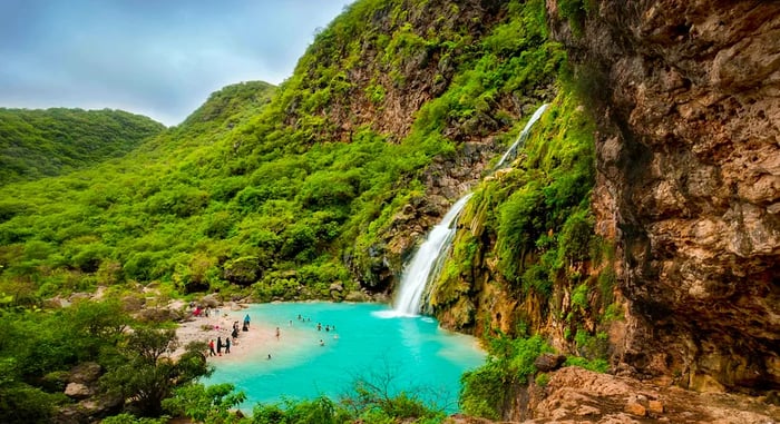 Aerial view of the Ayn Khor waterfalls nestled among lush greenery in Salalah, Oman.