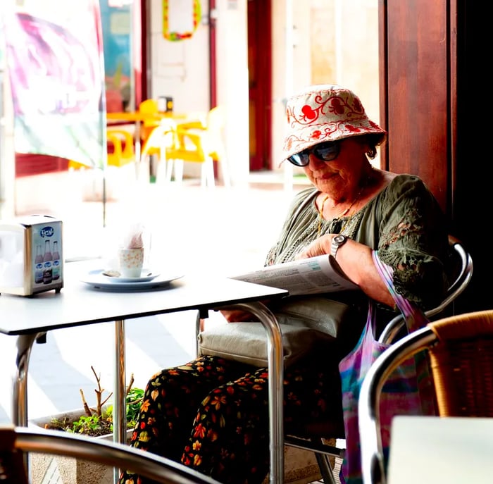 An elderly patron sits by the window, engrossed in reading the newspaper.