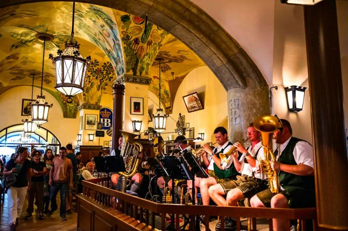 Musicians in traditional attire perform in the beautifully adorned hall of the Hofbräuhaus, Munich