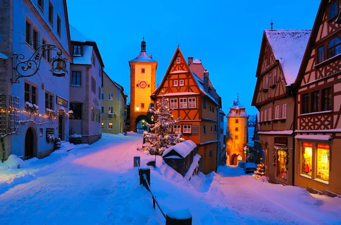 Snow covers the streets in this view of the Sieber Tower and Kobolzeller Tower in the historic town of Rothenburg ob der Tauber, Bavaria.