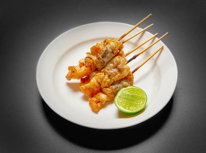 A selection of skewers served on a plate with a lime wedge.