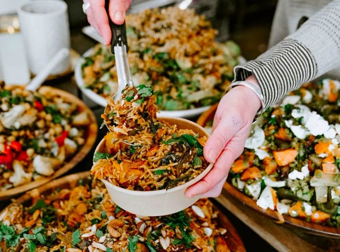 A server portions a grain salad into a bowl.