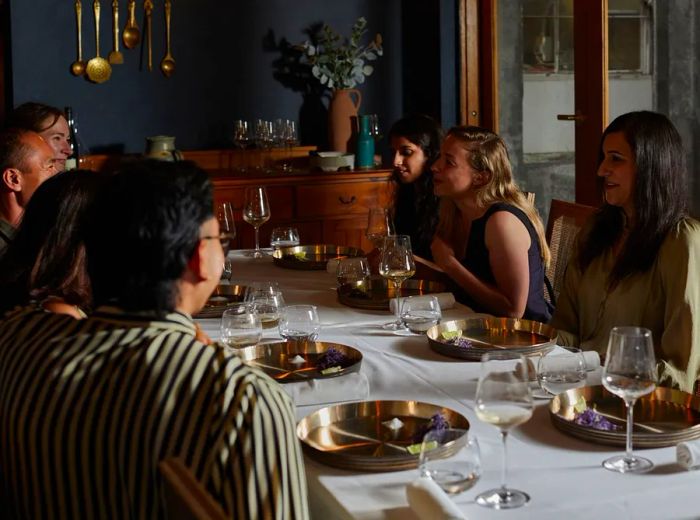 Diners gather around a communal table engaged in conversation.