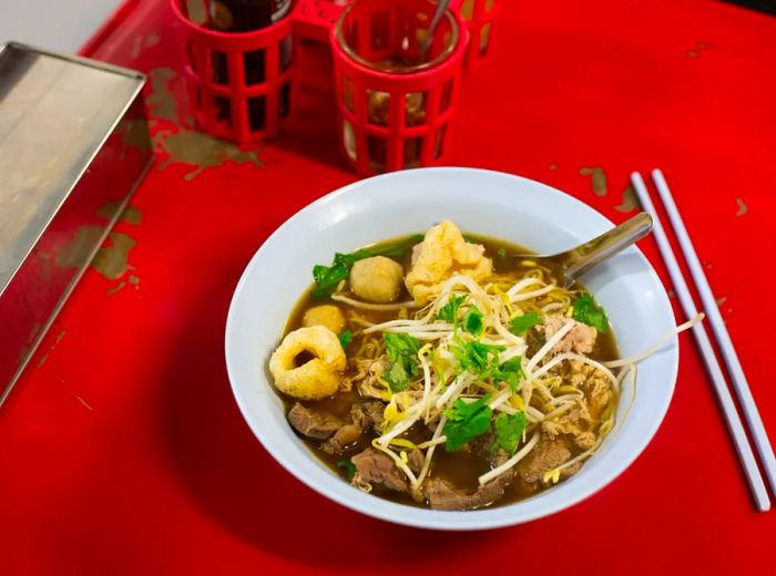 A bowl of boat noodles on a red tablecloth at Soi 38