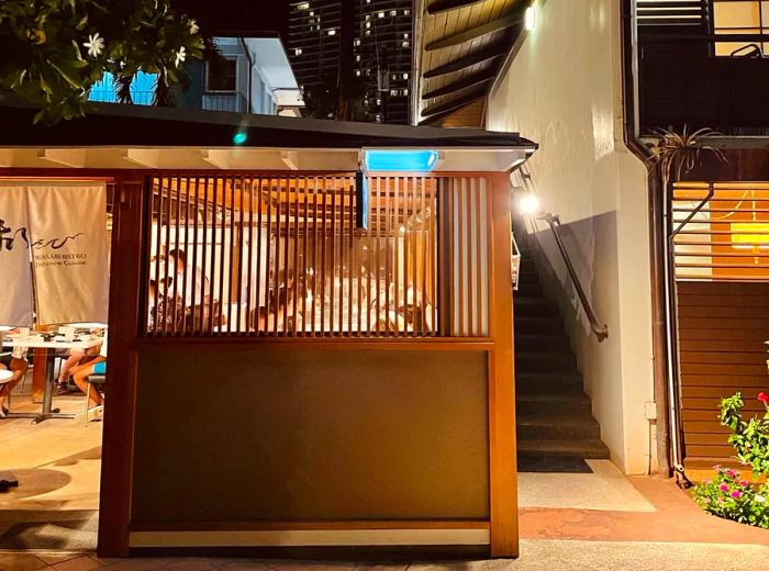 An outdoor dining area at a restaurant, visible through the slats of a wooden partition.