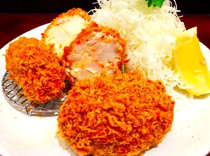 A close-up shot of croquettes served alongside shredded cabbage and a wedge of lemon.