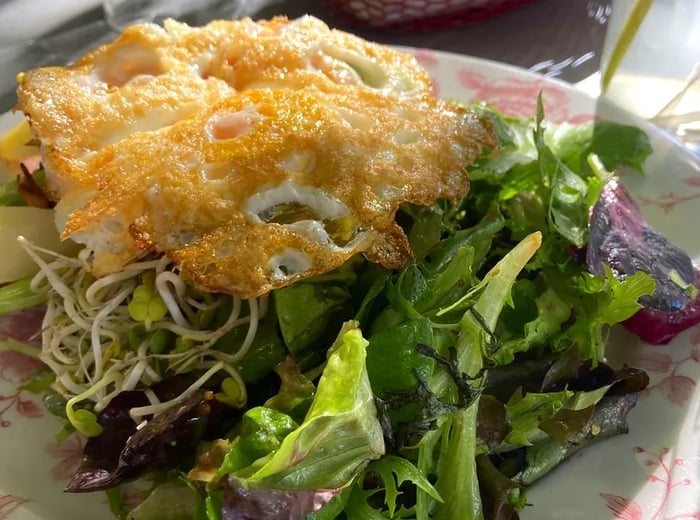 A decorative plate showcasing a salad topped with fried eggs.