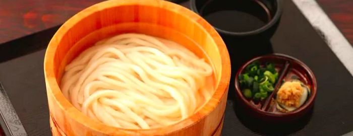 Noodles swimming in a rich soup within a deep wooden bowl.