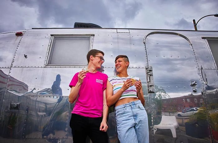 The founders stand beside an airstream trailer, proudly holding their ice cream sandwiches.