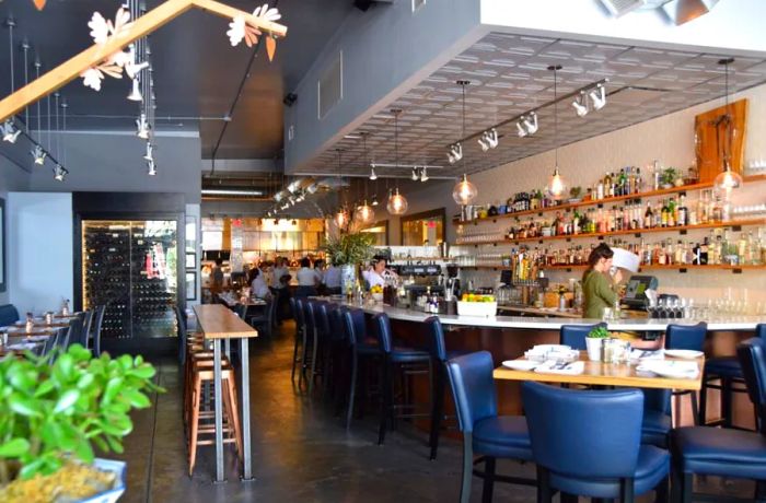 A dining area featuring a long bar, tables, a wine cooler, and charming decor