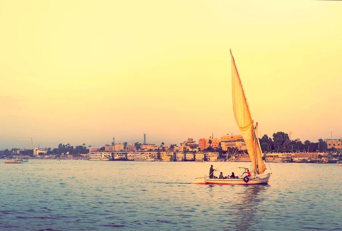 Experience a romantic sunset cruise on the Nile aboard a felucca, a traditional Egyptian sailboat, with the stunning skyline of Luxor in the background.