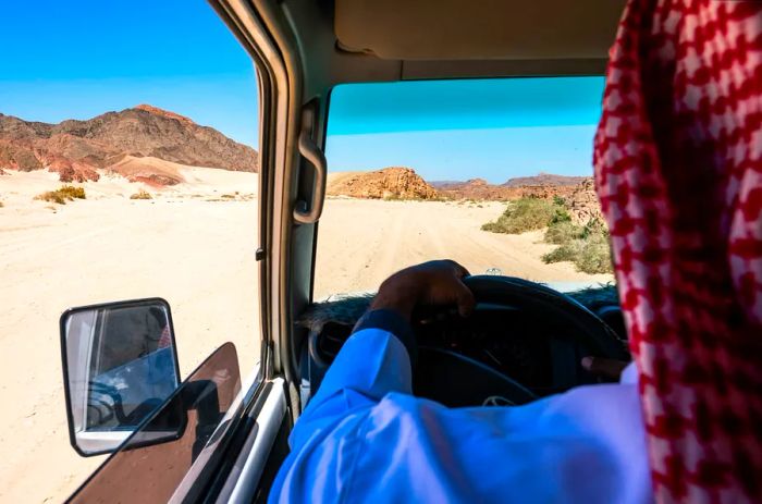 A man driving a vehicle across the desert.