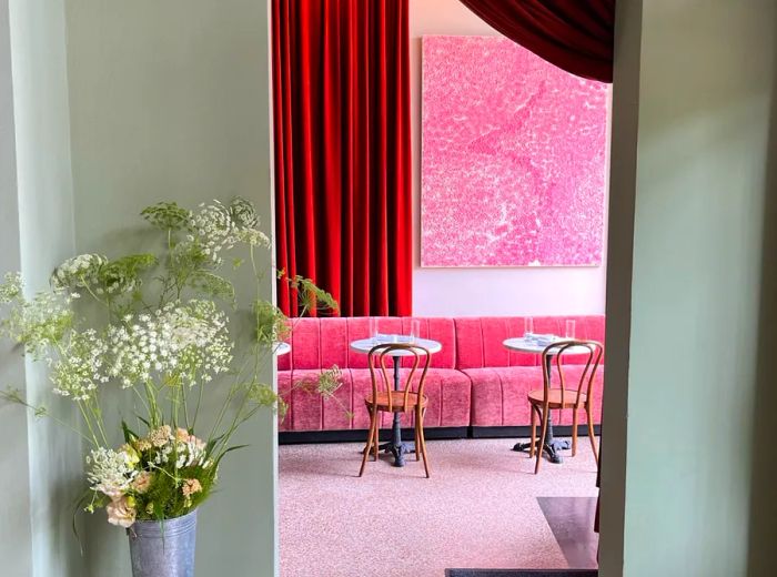 A glimpse into the restaurant's interior through an archway, showcasing pink banquettes and elegant decor.