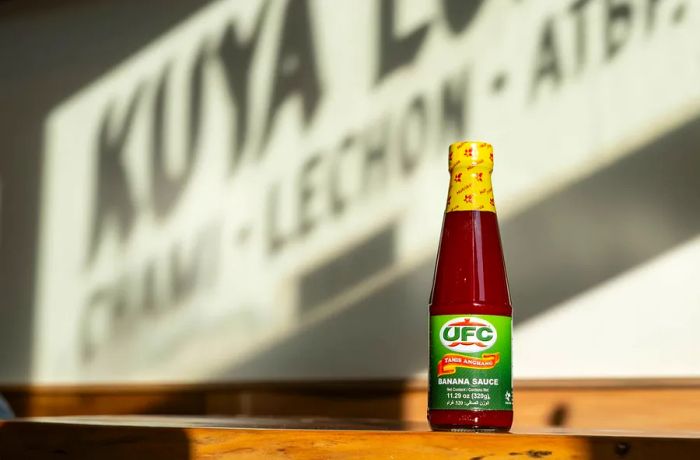 A green-labeled bottle of UFC brand banana ketchup rests on a table.