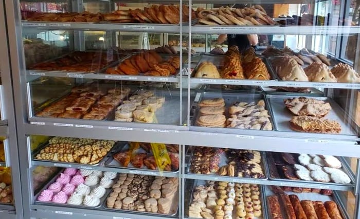 Brightly colored, decorative cookies and pastries are displayed in large sunlit pastry cases.