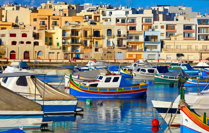 Vibrant Maltese fishing boats alongside traditional Maltese homes in St George's Bay